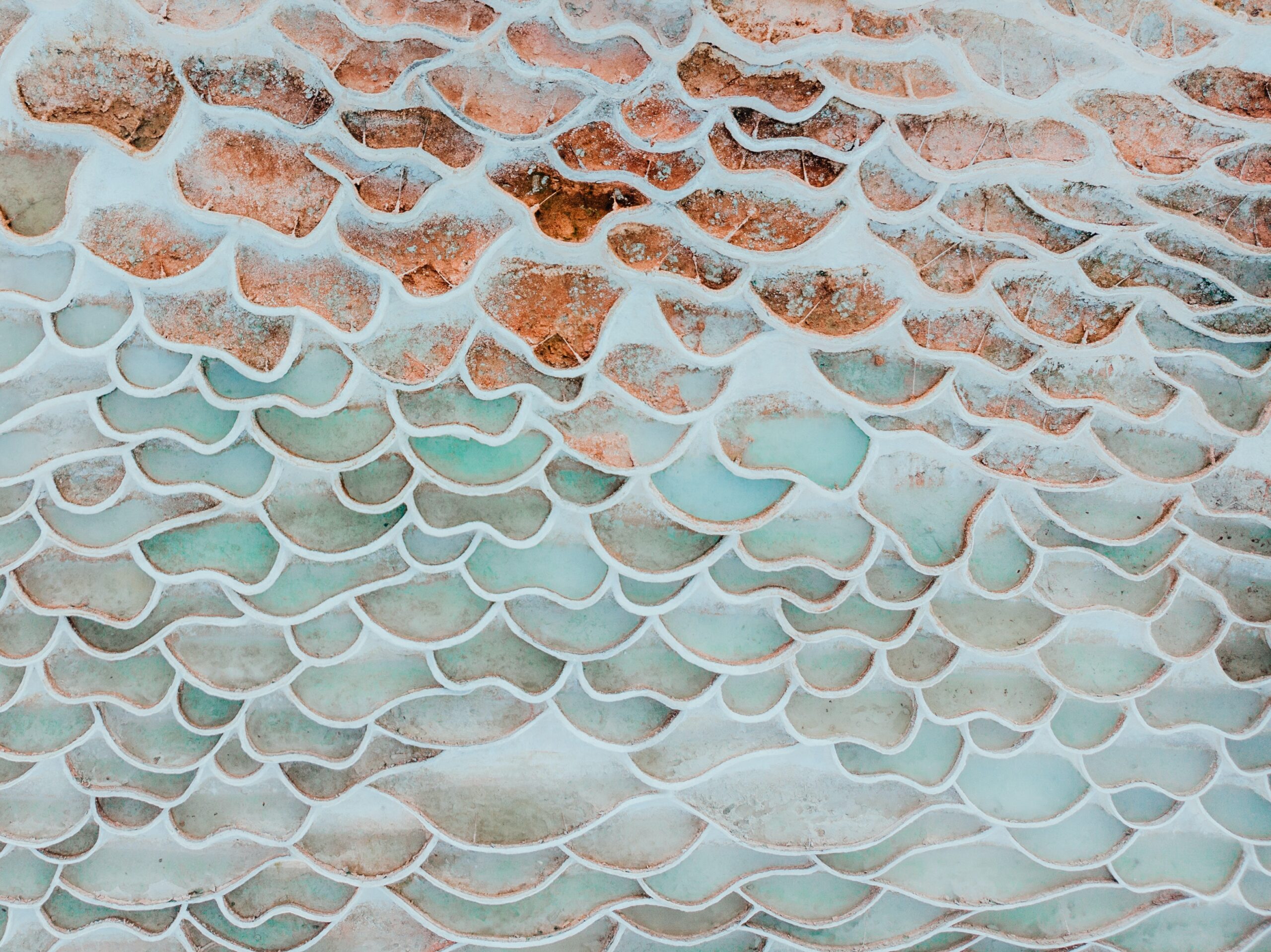 ripples in sandstone or travertine terraces with shades of pink, orange, and pale blue